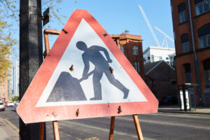 Roadworker sign on the road, red triangle with a man in the middle