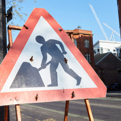 Roadworker sign on the road, red triangle with a man in the middle