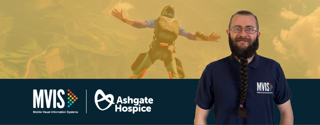 Worker in navy polo, stood infront of Skydiver for Charity Skydive