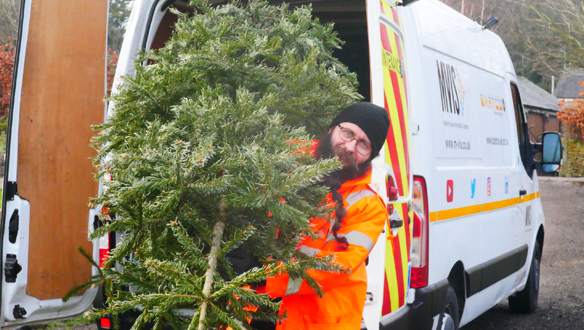 Man in high vis carrying a Christmas tree for Treecycle