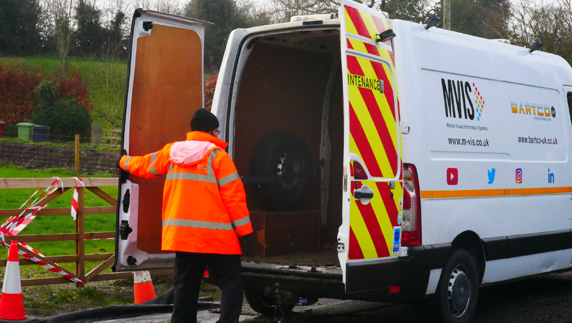 man in high vis closing a white van door in a country park